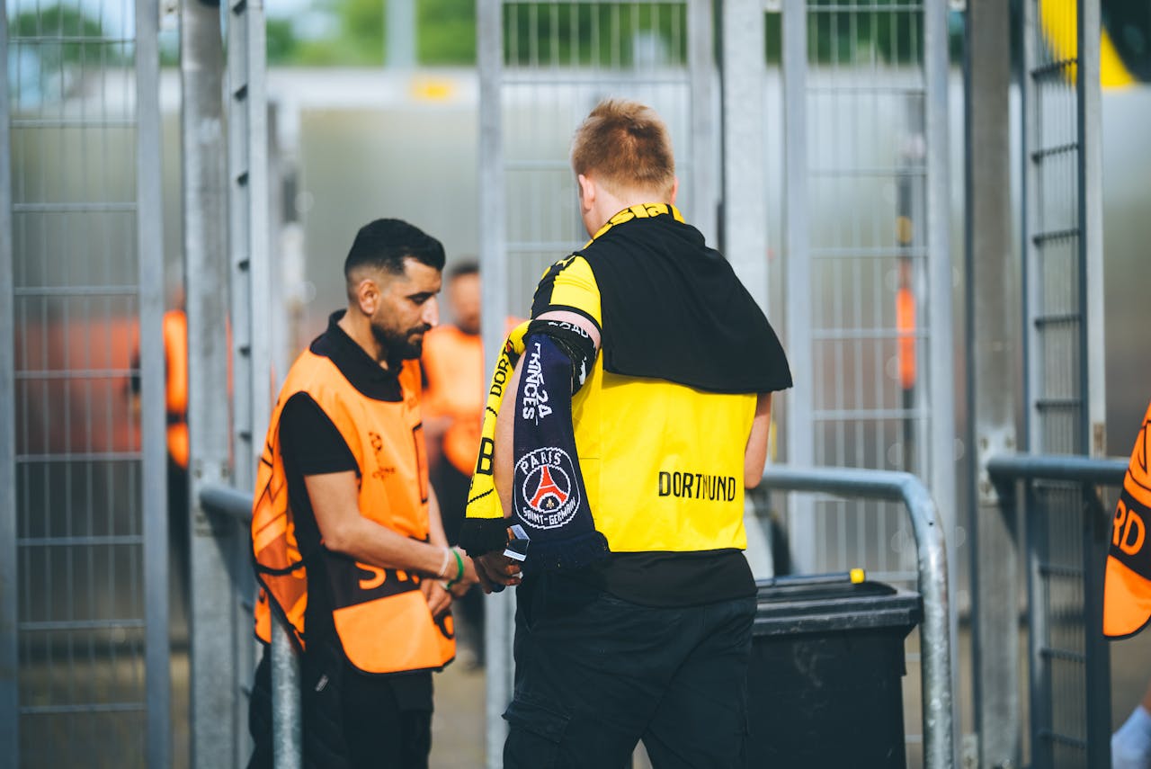 Security personnel and a fan at a football stadium checkpoint in Dortmund, Germany.